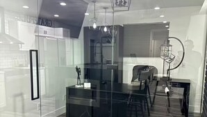 Una cocina moderna con separador de vidrio, suelo de madera y luminarias contemporáneas.