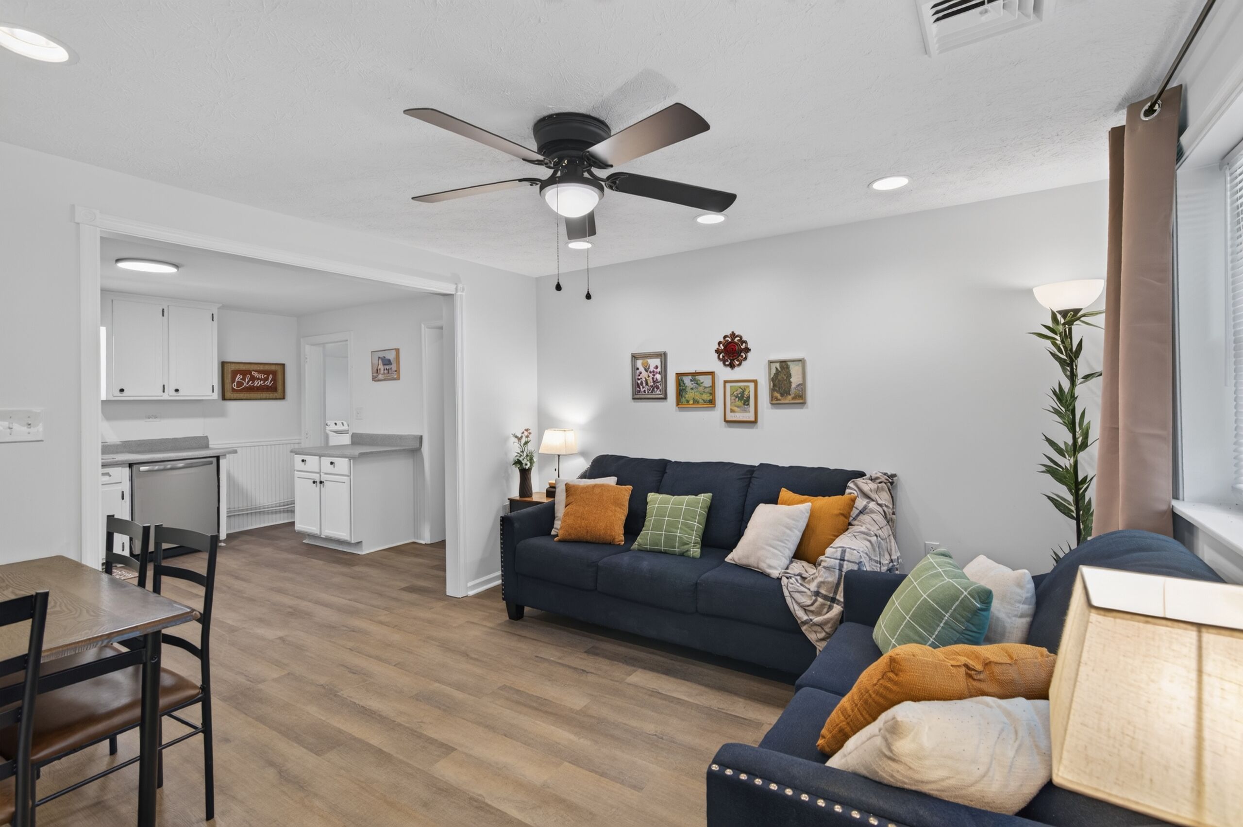 Un salon moderne avec un canapé bleu foncé, une table à manger en bois et un ventilateur de plafond.