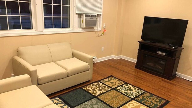 Un salon avec un canapé, un téléviseur et un tapis à motifs.