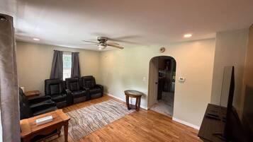 A living room with a ceiling fan, a sofa set, a coffee table, and a TV stand.