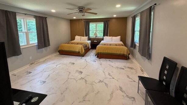 A bedroom with two beds, a ceiling fan, and a large window.