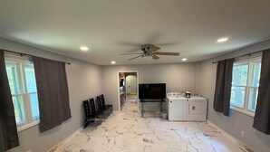 A spacious room with a large ceiling fan, a TV, a stove, and a washer and dryer.