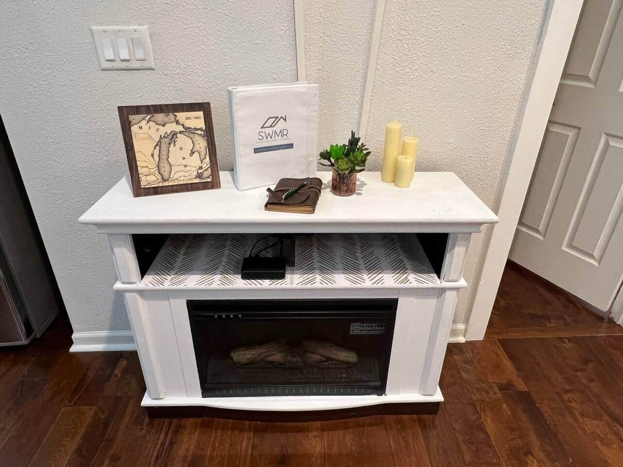 Ein weißer Kamin mit aufgelegtem gerahmten Stadtplan und einem SWMR-Kasten.