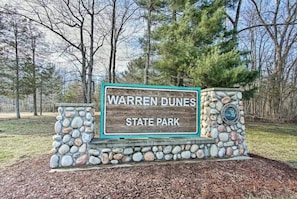 Un panneau indiquant l’entrée du parc d’État de Warren Dunes, avec un mur en pierre et un logo.