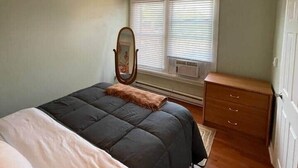 A bedroom with a bed, a ceiling fan, a dresser, and a window with blinds.