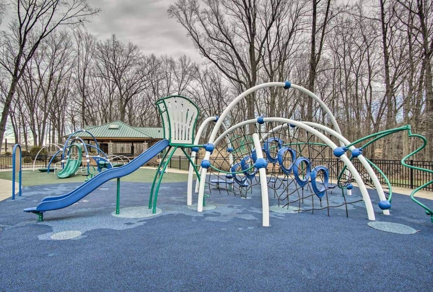 Ein Spielplatz mit Rutschen, Klettergerüsten und einem überdachten Sitzbereich.