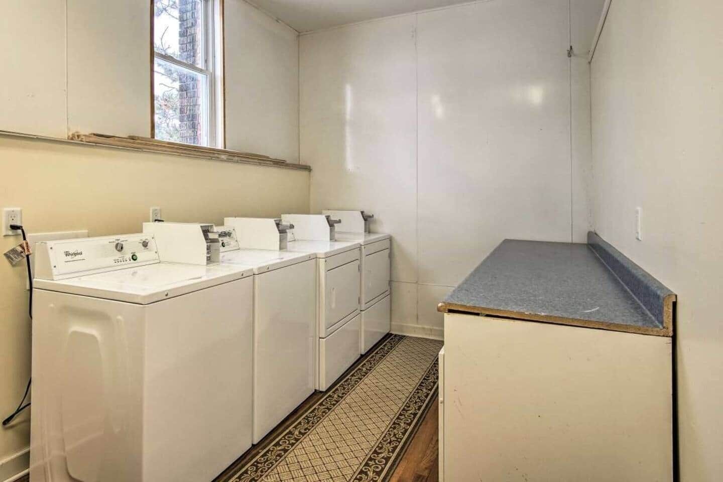 Una sala de lavandería con lavadora, secadora y una pequeña encimera.