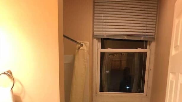 A small bathroom with a toilet, a shower, and a window.