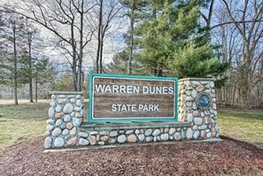 En skylt för Warren Dunes State Park, med en stenmur och en logotyp.