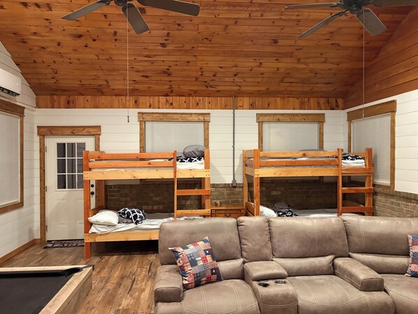Una habitación con literas de madera, un sofá de cuero y un ventilador de techo.