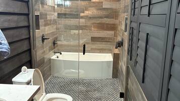 Une salle de bain moderne équipée d’une douche, de toilettes et d’une baignoire.