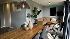 A modern living room with a wooden dining table, grey sofas, and a large plant. - Holiday Home in Lochem With Terrace (Lochem)