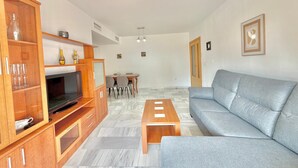 A living room with a sofa, TV, wooden cabinet, and a ceiling fan. - Terrasol Costaluz Torre del Mar (Torre del Mar)