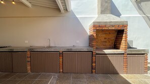 Une cuisine équipée d’un four en briques, d’un évier et d’une fenêtre donnant sur un patio.