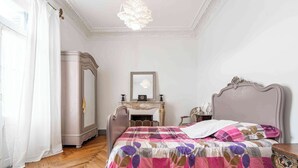 Un dormitorio con cama, cómoda, espejo y chimenea.