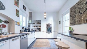 Una cocina moderna con armarios blancos, horno empotrado y cafetera.