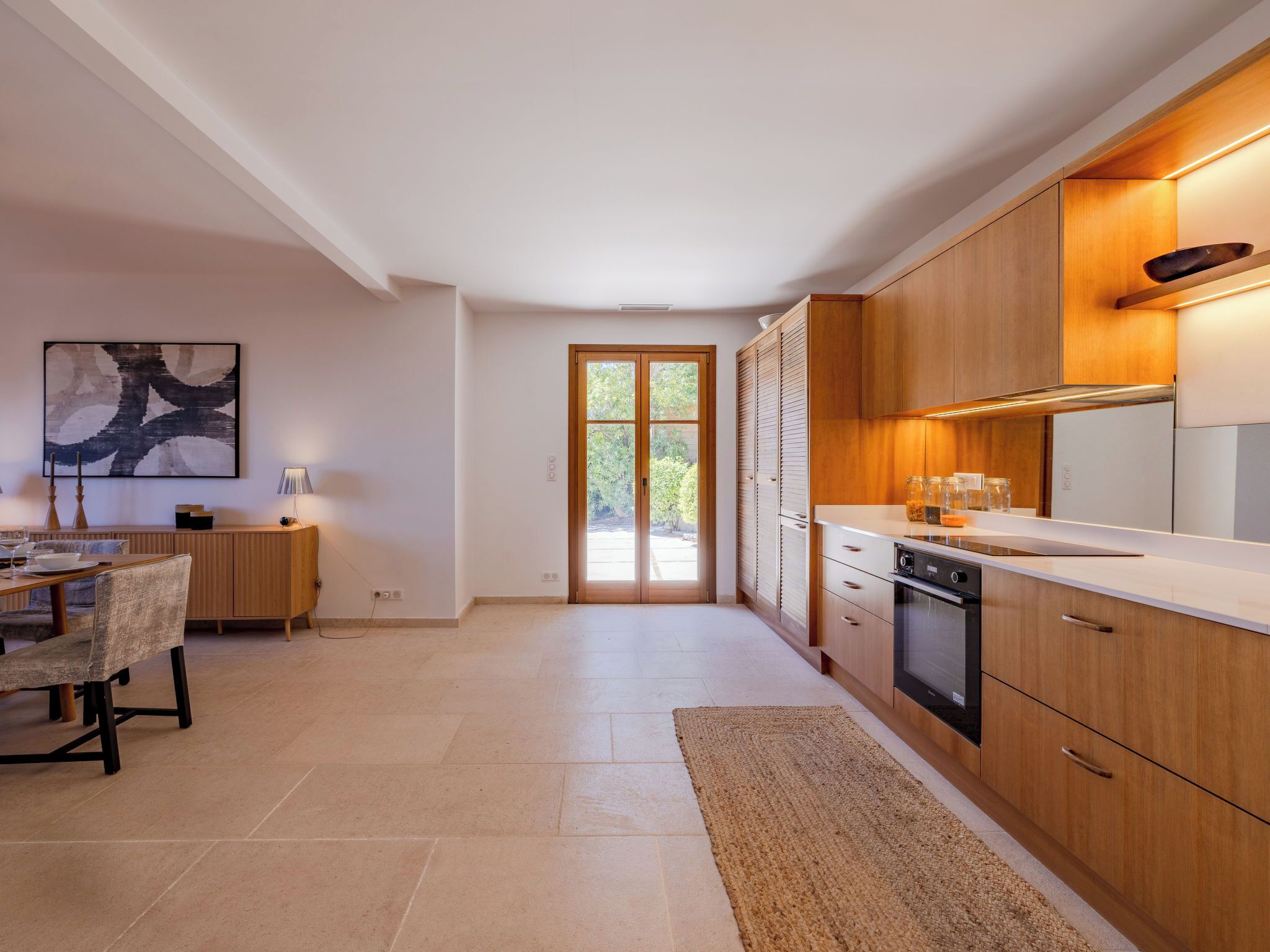 A modern kitchen with wooden cabinets, a built-in oven, and a large window.
