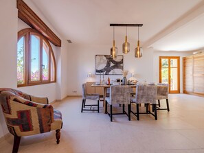 Un comedor con mesa de madera, sillas y lámparas colgantes.