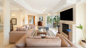 A spacious living room with a large sofa, a flat-screen TV mounted on the wall, and a fireplace.