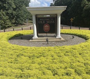 A welcome sign for Ole Miss with a classical column structure and a landscaped garden.