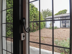 A view through a metal gate with a concrete pathway leading to a building with a tiled roof. - The Olde Forge (Minehead)