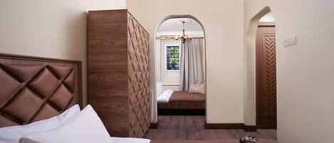 A hotel room with a bed, a wooden headboard, a small seating area with a view, and a tray with breakfast items.