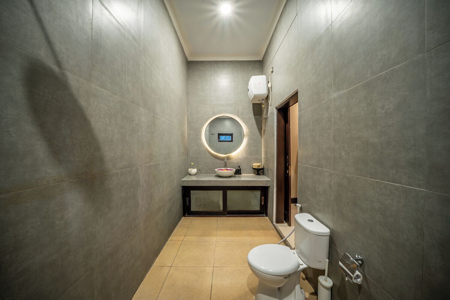 Une petite salle de bain comprenant des toilettes, un lavabo avec un miroir et une pomme de douche.
