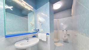Un bany modern amb un lavabo, mirall i plat de dutxa.