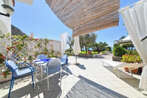An outdoor patio with a table and chairs, surrounded by potted plants and a view of the sea. - Cobalt (Barano D'ischia)
