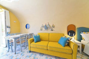 A yellow sofa with blue cushions, a dining table with chairs, and a wall with nautical decorations. - Cobalt (Barano D'ischia)