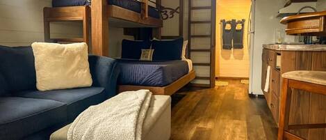 Ein gemütliches Zimmer mit einer Couch, einem kleinen Bett, einem Holzschrank und einer Küchenzeile.