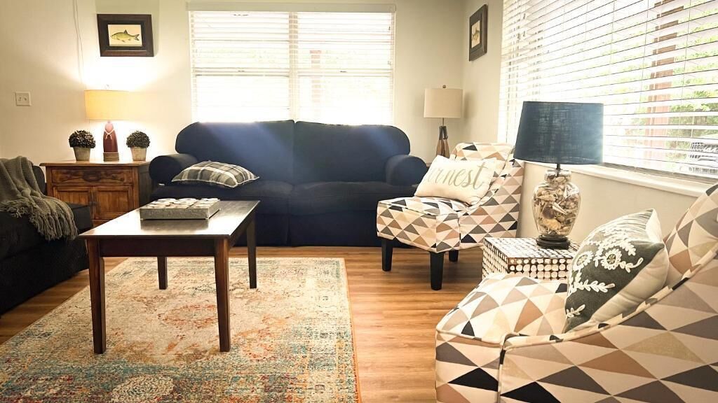 A living room with a sofa, armchair, coffee table, and lamps.