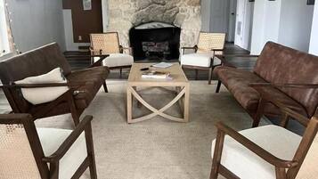 Un salon avec une cheminée en pierre, un ventilateur de plafond et un téléviseur.