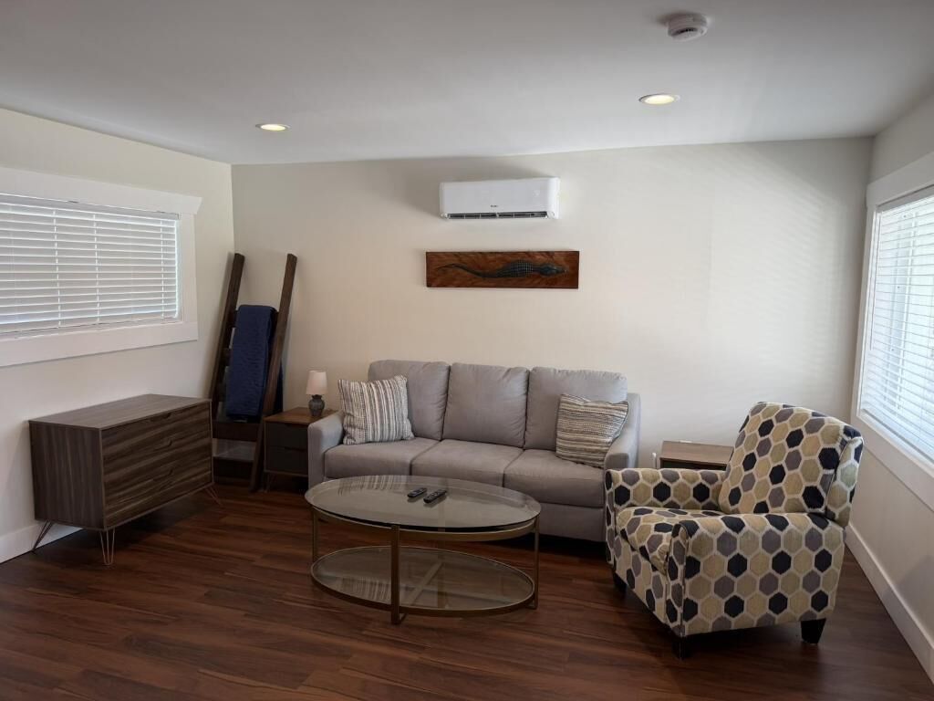 A living room with a sofa, armchair, coffee table, and a painting on the wall.