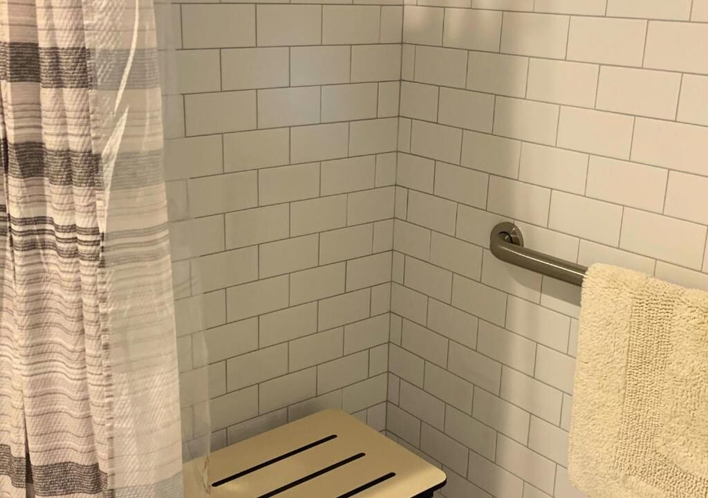 A shower area with white tiled walls, a shower curtain, and a towel rack.