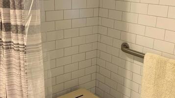 A shower area with white tiled walls, a shower curtain, and a towel rack.