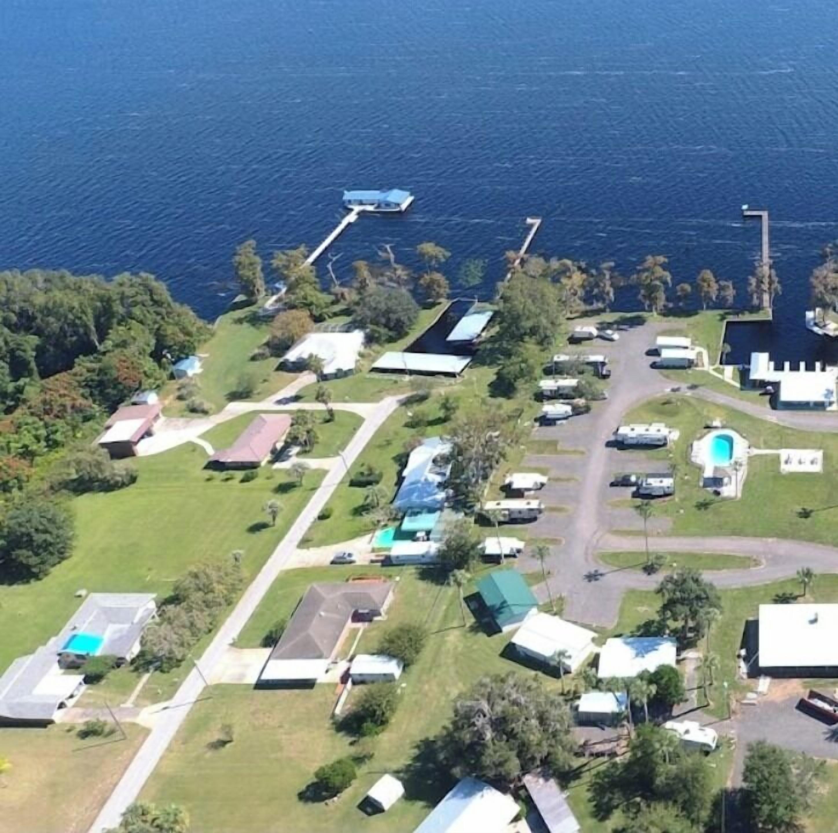 Vista aérea de una zona residencial costera con casas, un muelle y una piscina.