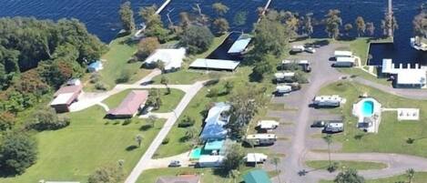 Vista aérea de una zona residencial costera con casas, un muelle y una piscina.
