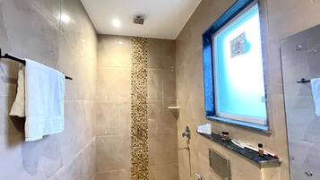 Un baño con ducha revestida de azulejos, una ventana y un perchero.
