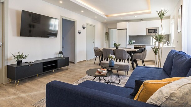 Un salon moderne doté d’un téléviseur à écran plat, d’un canapé, d’une table basse et d’un coin repas avec des chaises.