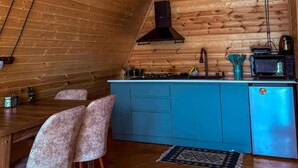 A kitchen with wooden walls, a blue cabinet, a gas stove, and two chairs.