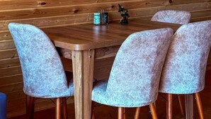A wooden dining table with four chairs, a small statue, and a wall-mounted security camera.