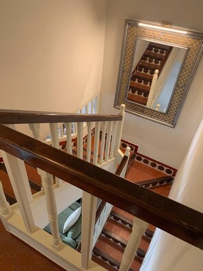 Eine Treppe mit weißen Balustern und dunklen Holzhandläufen, die zu einem Podest mit einer Wand führt, die die Treppe spiegelt.