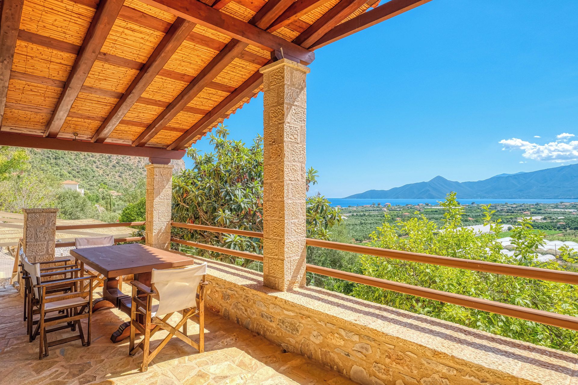 A covered outdoor seating area with stone walls and a view of a mountainous landscape.