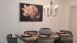 En matplats med ett träbord, sex stolar, en kristallkrona och en blomstermålning på väggen.