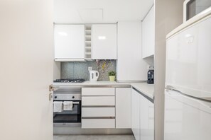 A modern kitchen with white cabinets, a stove, a kettle, and a coffee machine. - Rossio Boutique Apartment 1 – Perfect for Couples and Small Families (Lisbon)