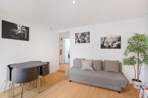 A modern living room with a grey sofa, a black dining table, and a potted plant. - Rossio Boutique Apartment 1 – Perfect for Couples and Small Families (Lisbon)