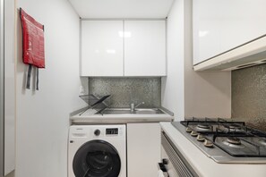A compact kitchen with a washing machine, a sink, and a gas stove. - Rossio Boutique Apartment 1 – Perfect for Couples and Small Families (Lisbon)
