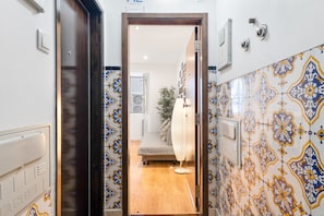 A hallway leading to a room with patterned tile walls, a bed, and a radiator. - Rossio Boutique Apartment 2 (Lisbon)