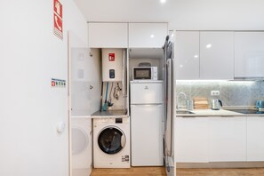 Eine kleine Küchenzeile mit Waschmaschine, Mikrowelle und Spüle.